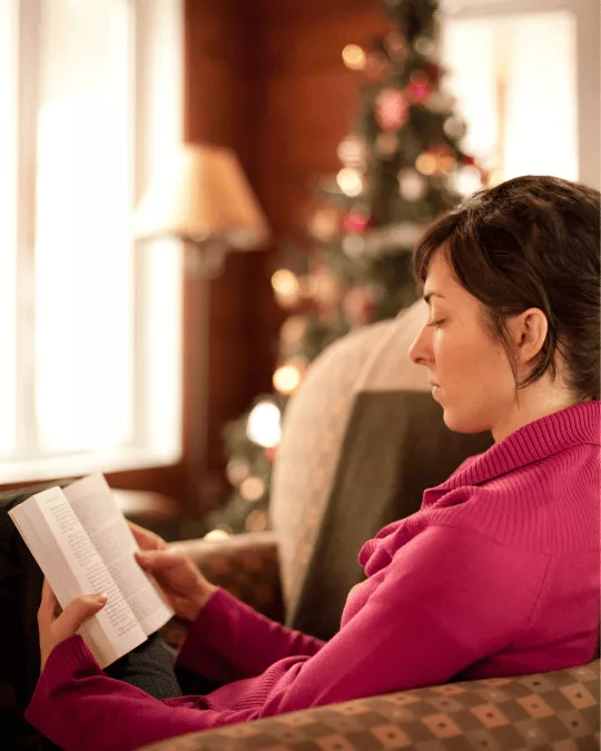 Person reading near Christmas tree